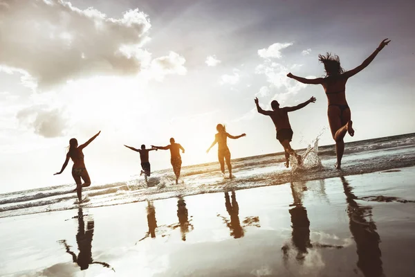 Groupe heureux jeunes gens courir saut plage — Photo