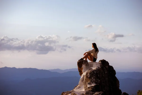 Gyönyörű lány ül a nagy rock naplementekor — Stock Fotó