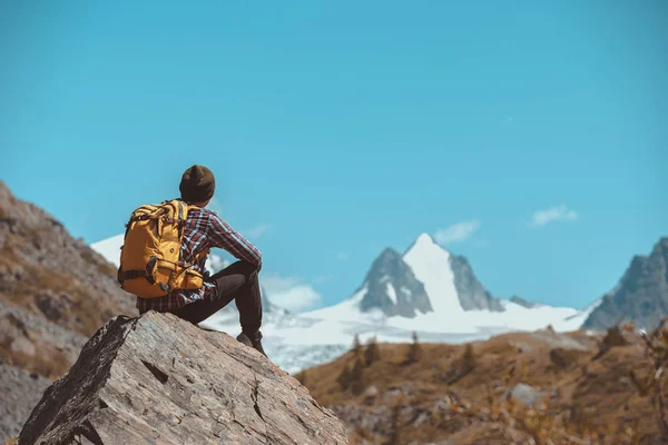 Caminante se sienta en la roca grande y mira a la montaña — Foto de Stock