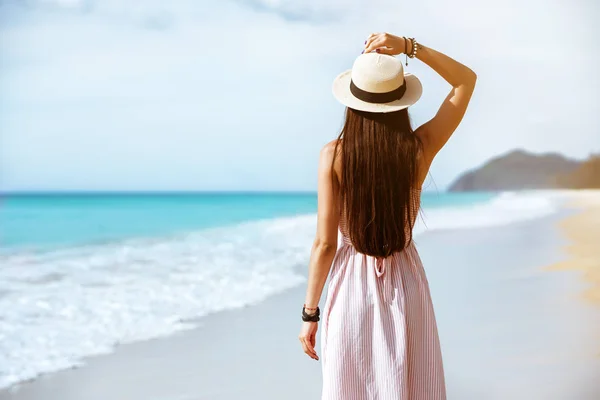 苗条的女士在礼服和帽子走在海滩 — 图库照片