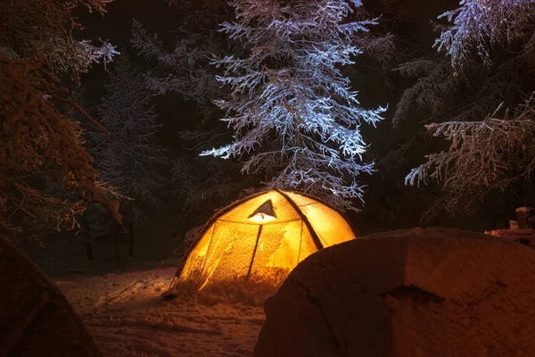 Night winter camp with tents in snowy forest