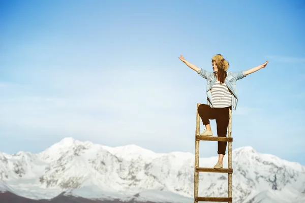 Счастливая девушка на деревянной лестнице с поднятыми руками — стоковое фото