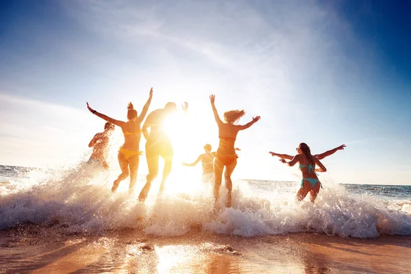 Grande grupo feliz amigos corre e se divertindo no pôr do sol praia — Fotografia de Stock