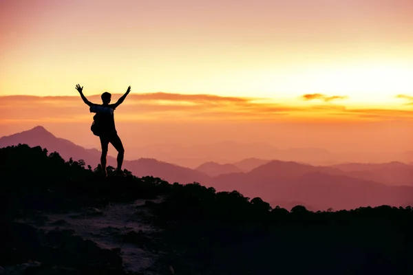 Hikers silhouette stands on mountain top against sunset — Stock Photo, Image