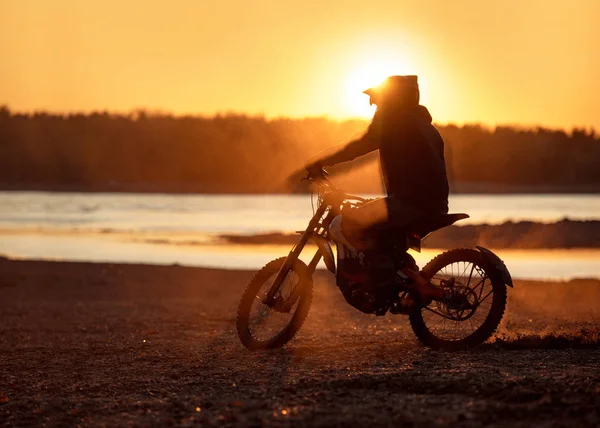 सूर्यास्ताच्या वेळी ई-मोटारसायकलवर मोटारसायकल चालक सिल्हूट — स्टॉक फोटो, इमेज