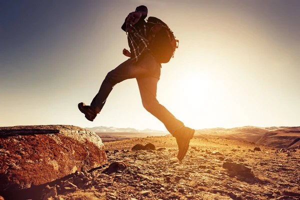 Uomo con zaino salta alla grande roccia — Foto Stock