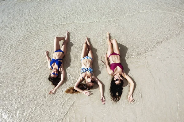Three beautiful ladies in swimsuits at sea beach — ストック写真