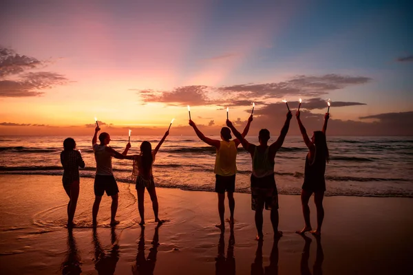 Grand groupe d'amis avec des feux de bengale sur la plage — Photo