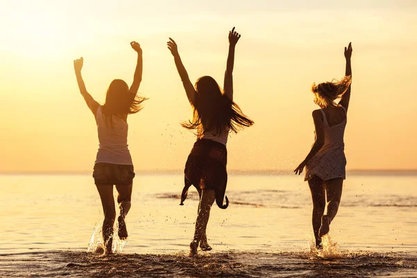 Drie gelukkige meisjes op caml zee strand en zonsondergang — Stockfoto