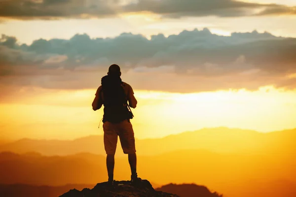Turista s batohem stojí na hoře při západu slunce — Stock fotografie