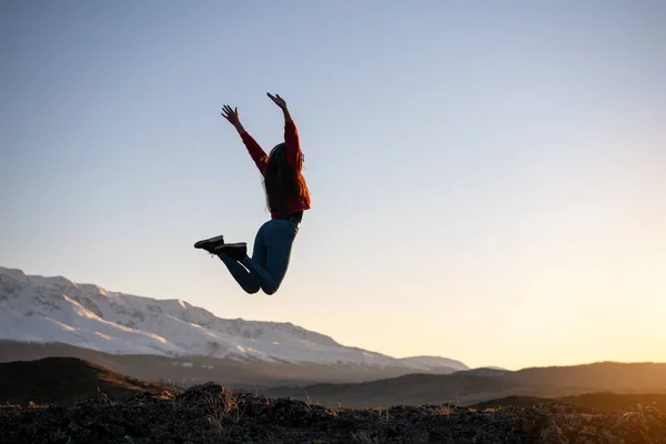 Schlankes Mädchen springt gegen Berge und Sonnenuntergang — Stockfoto