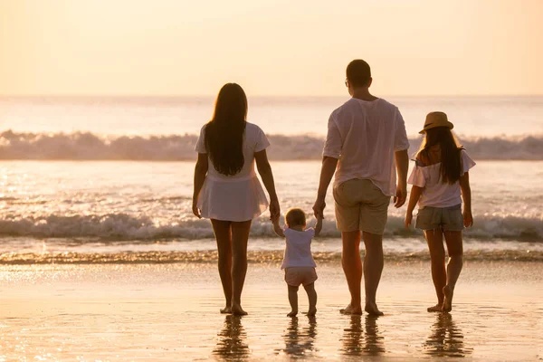 Família de quatro pessoas relaxando na praia do pôr do sol — Fotografia de Stock