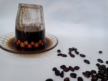 Kahve çekirdekleri etrafa saçılmış, kahve fincanında servis edilen taze demlenmiş kahve, yaşam tarzı ve kafe kültürünü temsil ediyor..