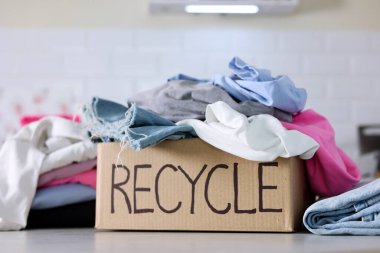 Giysilerle dolu renkli bir kutu, açıkça Geri Dönüşüm etiketi ile, sürdürülebilir ve eko-dostça moda tercihlerini destekliyor