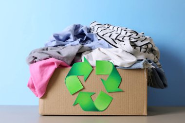 Renkli bir kıyafet yığını, tekstil geri dönüşümünün önemini ön plana çıkarıyor ve çevreye dost unsurlar sunuyor.