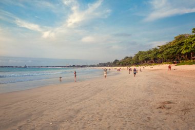 Bali, Endonezya - 17 Ekim 2018: Jimbaran kumsalda gün batımından önce yürüyen turist