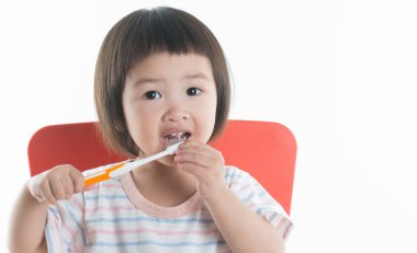 Asyalı çocuk beyaz arka plan üzerinde diş fırçası kız ile dişlerini temizleme.