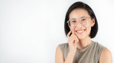 Kısa siyah saçlı, beyaz dişli ve büyük gözlüklü sevimli bir Asyalı kadın mutlu bir şekilde gülümsüyor. Beyaz arka planda yüz ifadelerini ve gözlerini ifade eden ve uzayı kopyalayan başarılı olmaktan mutluyum.