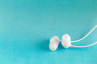 White earbuds on blue colorful background with copy space for text clipart