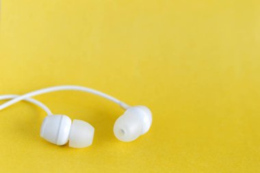 Sarı pastel arka planda beyaz kulaklıklar ve metin için kopyalama alanı