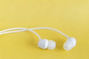 Sarı pastel arka planda beyaz kulaklıklar ve metin için kopyalama alanı