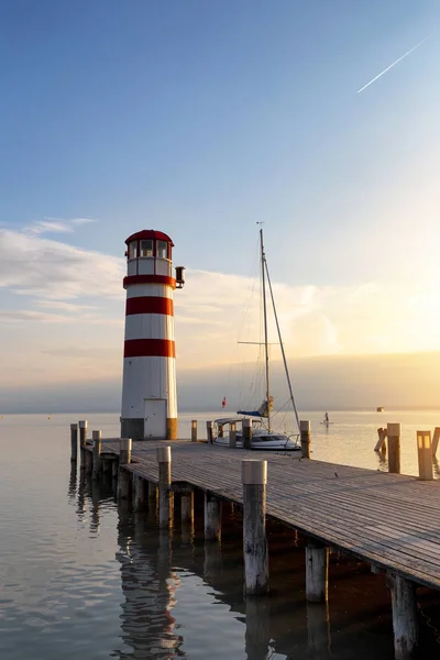 Deniz feneri ve günbatımı için bekleyen bir tekne