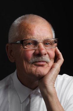 Dalgın yaşlı adam gözlüklü siyah bir zemin üzerine