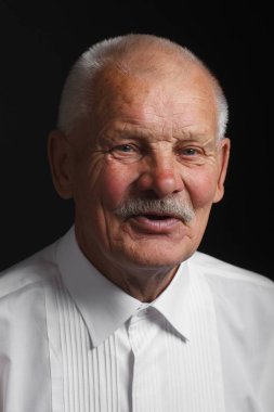 Siyah bir zemin üzerine beyaz gömlekli olumlu yaşlı adam