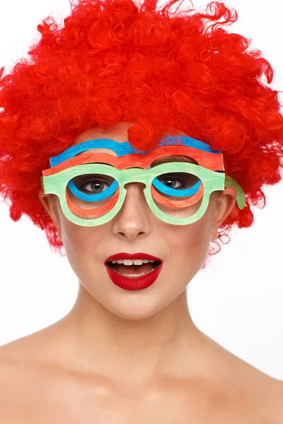 彼女の頭の上の赤いかつらと一緒にピエロのイメージで若い女性の肖像画 自家製のメガネで — ストック写真