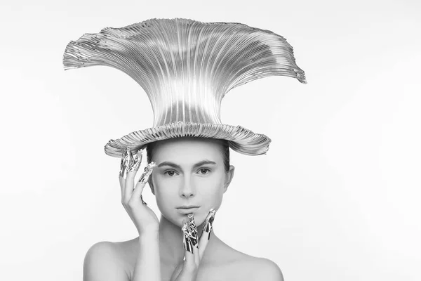 Beautiful woman in a futuristic style, with an iron hat on her head and with fingers that are wrapped in foil. White background