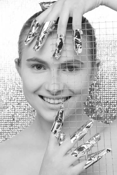 Portrait of a young beautiful woman on a futuristic background, with fingers wrapped in foil