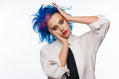 Studio bir beyaz gömlek ve siyah kravat giymiş mavi ve pembe saçlı bir kadın portresi. Beyaz arka plan