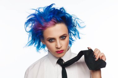 Studio bir beyaz gömlek ve siyah kravat giymiş mavi ve pembe saçlı bir kadın portresi. Beyaz arka plan