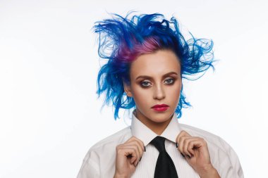 Studio bir beyaz gömlek ve siyah kravat giymiş mavi ve pembe saçlı bir kadın portresi. Beyaz arka plan