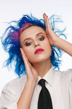 Studio bir beyaz gömlek ve siyah kravat giymiş mavi ve pembe saçlı bir kadın portresi. Beyaz arka plan