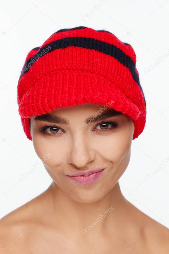 Portrait of an energetic beautiful woman with a red knitted hat on her head. White background