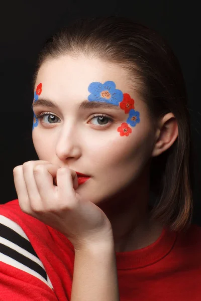 照片中 一个年轻女孩化妆 以红色和蓝色的鲜花形式 黑色背景 — 图库照片