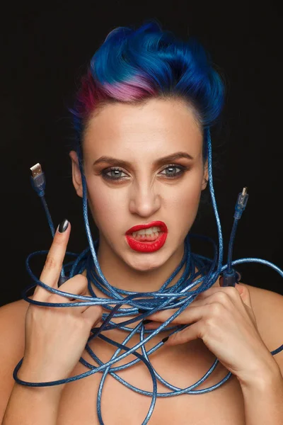 Portrait of an expressive emotional woman with blue and pink hair who is holding a long usb wire — Stock Photo, Image