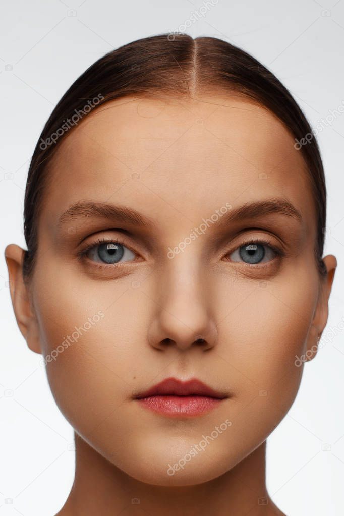 Close-up portrait of a beautiful model with clean makeup and collected hair, photographed in a photo studio