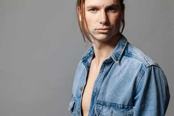 Portrait of a handsome long-haired man with freckles dressed in a denim shirt