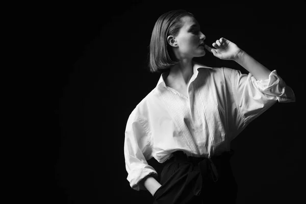 Retrato de una joven elegante con camisa blanca y pantalones negros. Interesante luz de estudio —  Fotos de Stock