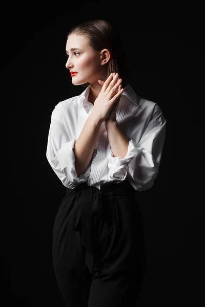 Портрет элегантной молодой женщины в белой рубашке и черных брюках. Интересный студийный свет — стоковое фото