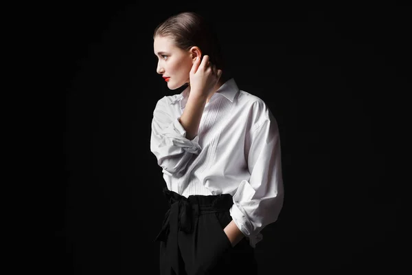 Retrato de uma jovem elegante com uma camisa branca e calças pretas. Luz de estúdio interessante — Fotografia de Stock