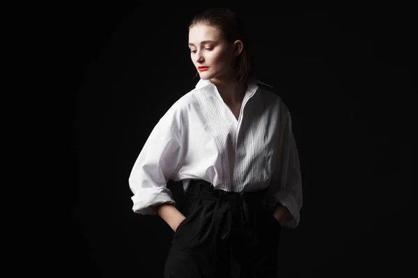 Retrato de uma jovem elegante com uma camisa branca e calças pretas. Luz de estúdio interessante — Fotografia de Stock