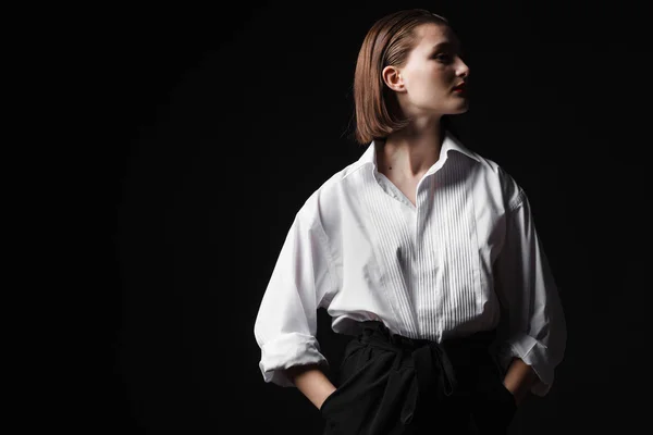 Retrato de una joven elegante con camisa blanca y pantalones negros. Interesante luz de estudio — Foto de Stock