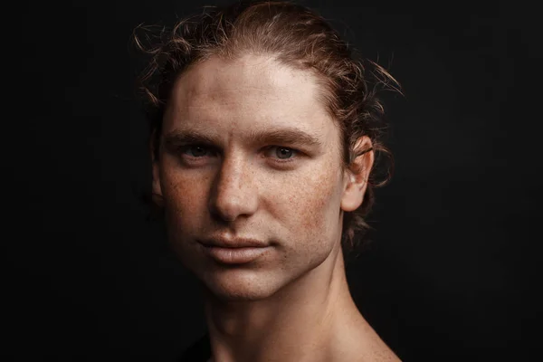 Portrait of a handsome long-haired man with drawn hair and freckles