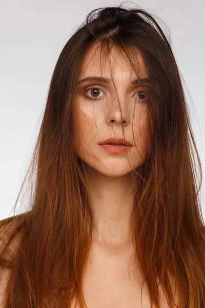 Porträt einer schönen Frau mit glatten langen Haaren und interessanten Emotionen. hellgrauer Hintergrund — Stockfoto