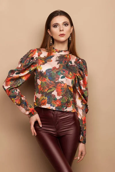 Фотография модели в яркой блузке и коричневых джинсах с высоким блеском, позирующей фотографу. Фотосессия студии — стоковое фото