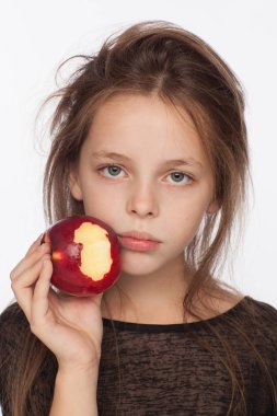 Bir elma ile güzel duygusal sekiz yaşındaki kız. Stüdyoda Fotoğraf oturumu. Kız bir siyah bluz giyiyor