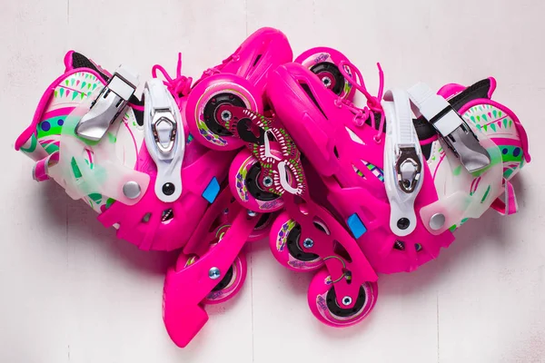 A pair of pink stylish roller skates on a white wooden background — Stock Photo, Image